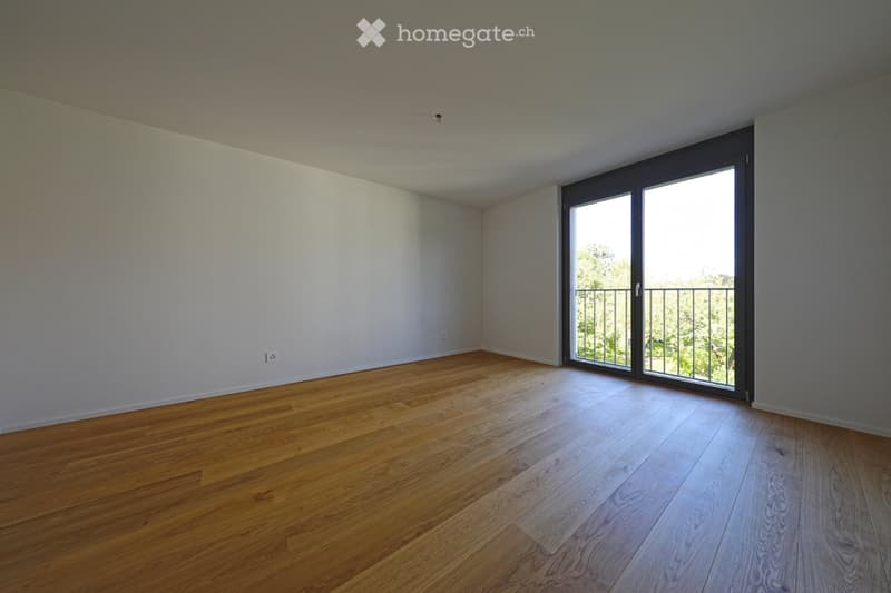 Empty room with wooden flooring, white walls, and large sliding glass doors leading to a balcony.