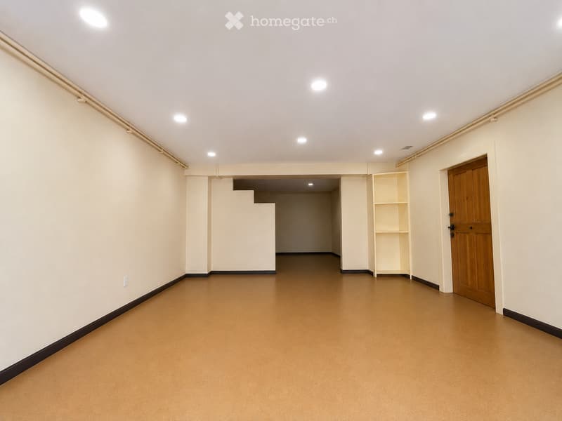 Empty room with light-colored walls, wooden floor, and a single wooden door. No furniture or equipment present.