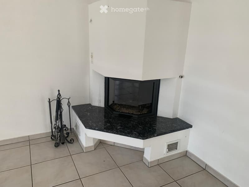 Empty room with a modern fireplace, black granite surround, and tiled floor.