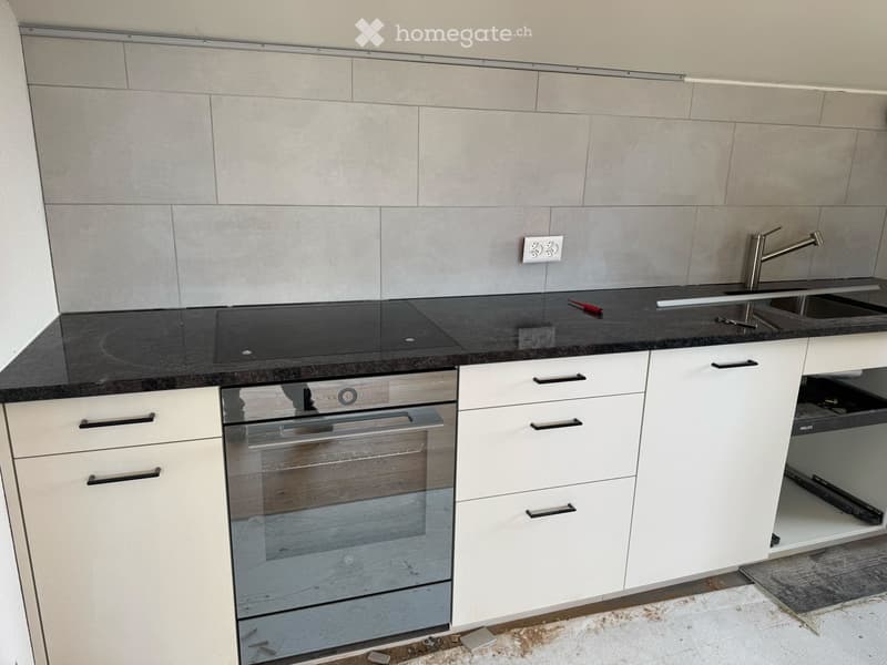 White cabinetry, black countertops, integrated oven, sink with faucet, power outlet, pull-out drawer