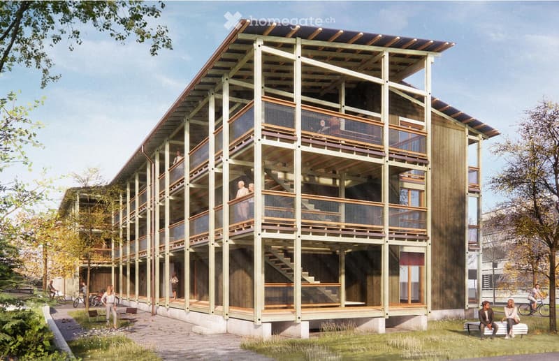 Modern multi-story building with wooden balconies and open walkways, surrounded by greenery and pathways.