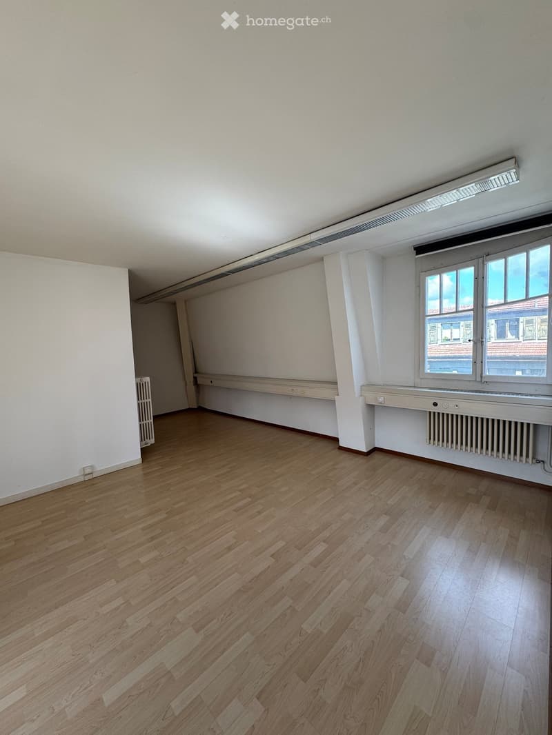 Empty room with wooden flooring, white walls, and a window with a radiator below it. No furniture or equipment is present.