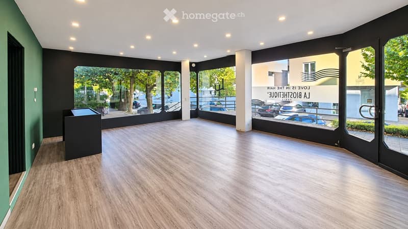 Empty room with wooden flooring, large windows, and modern lighting fixtures. No furniture or equipment present.