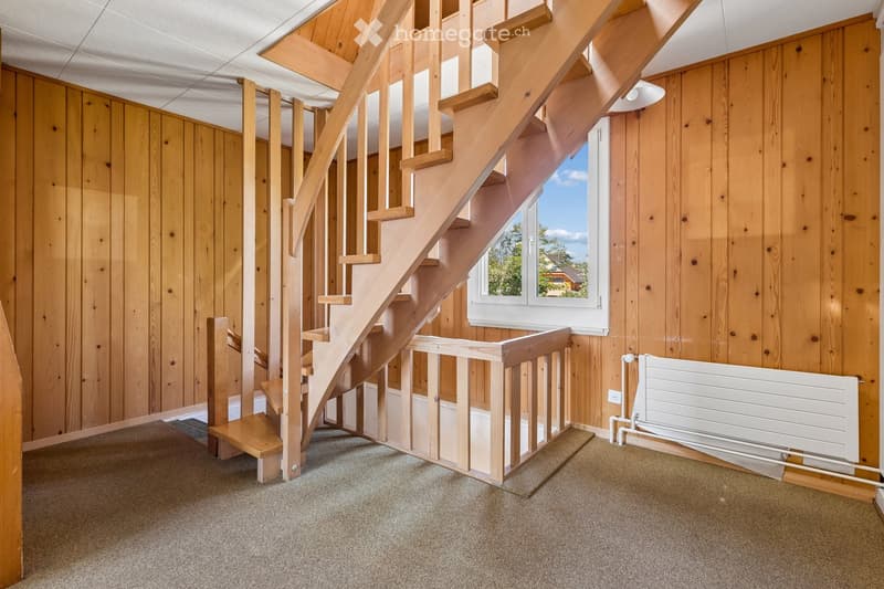 Wooden staircase with a railing, wooden walls, carpeted floor, and a white radiator on the right side.