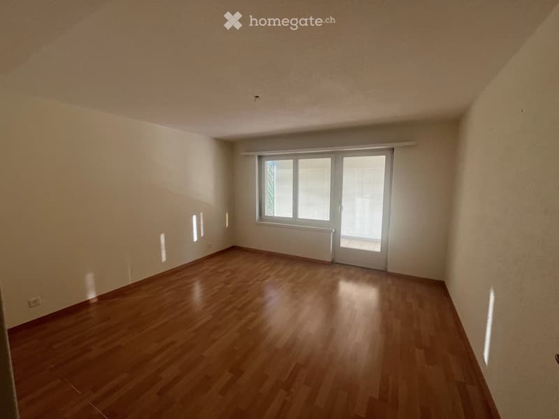 Empty room with wooden flooring, white walls, and a large window with blinds. No furniture or equipment is present.