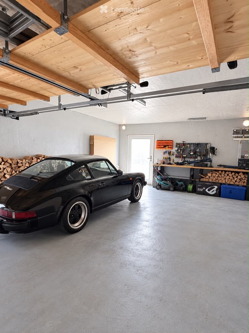 {"type": "Garage", "objects": ["car", "workbench", "tools", "storage bins", "lawn mower", "wood stack"], "description": "Modern garage with a sleek black sports car parked inside, wooden beams on the ceiling, workbench with tools, storage bins, and a stac