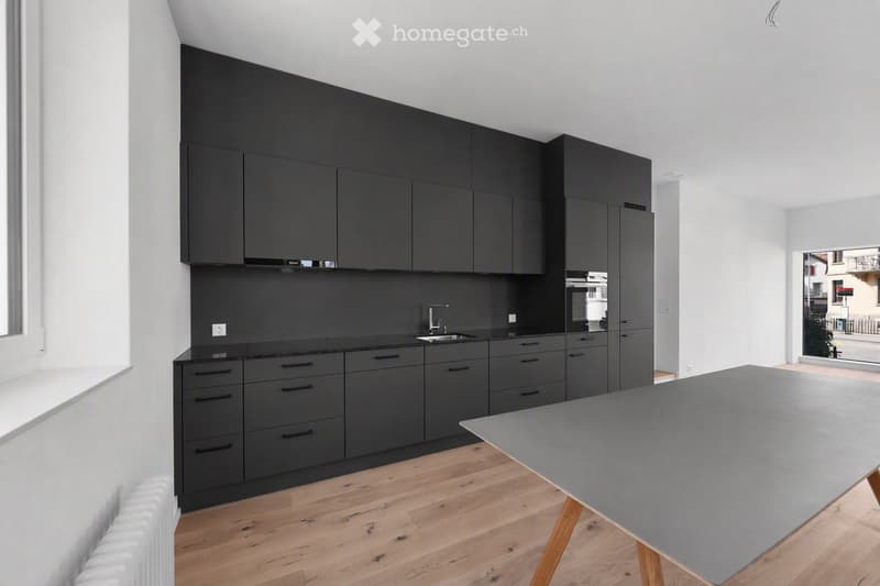 Modern kitchen with dark grey cabinets, a sink, and a grey table with wooden legs.