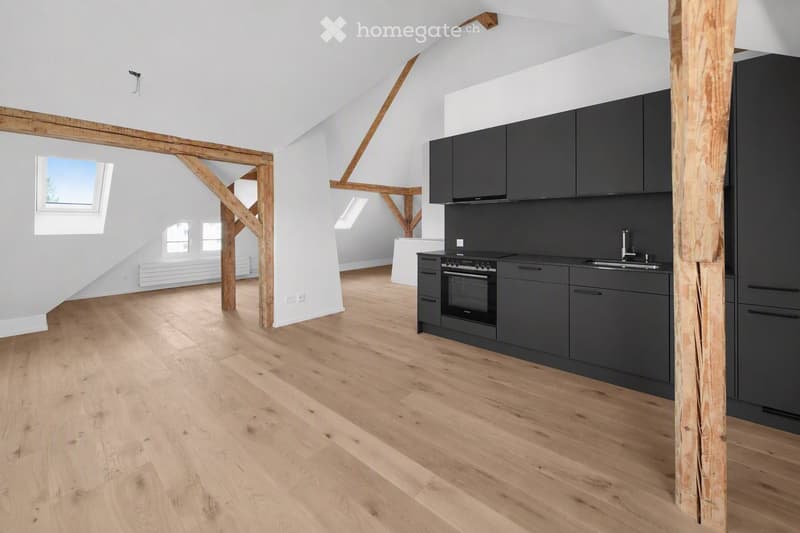 Modern kitchen with dark grey cabinets, a built-in oven, and a sink, featuring light wooden flooring and exposed wooden beams.