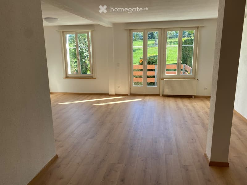 Empty room with wooden flooring, large windows, and a radiator. No furniture or equipment present.