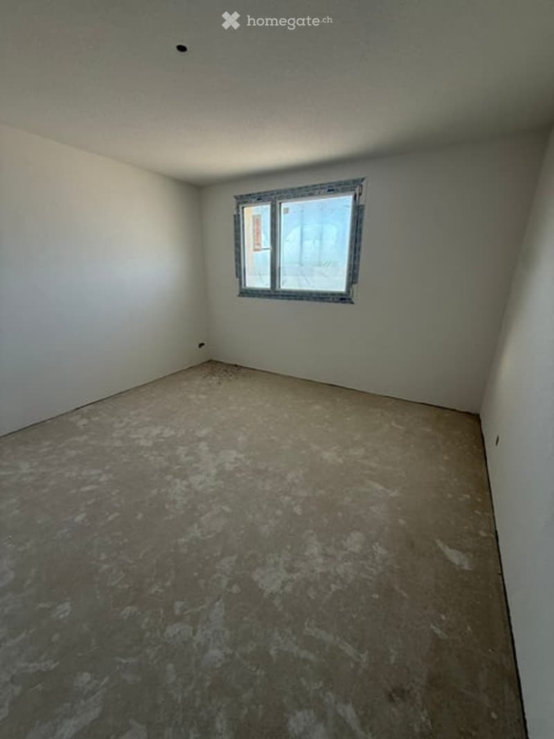 Empty room with bare walls and unfinished concrete floor, featuring a single window with metal frame.