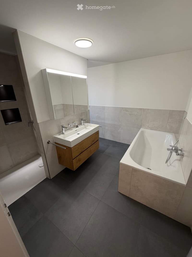 Modern bathroom with a freestanding bathtub, double sink vanity with wooden cabinet, large mirror, and sleek fixtures.