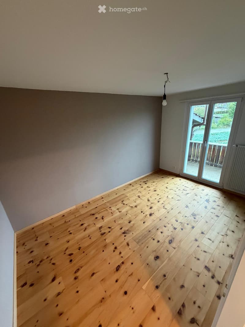 Empty room with wooden flooring and large sliding glass door leading to a balcony.