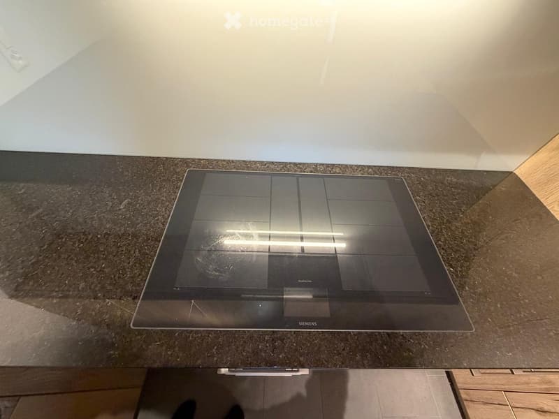 Modern kitchen with a sleek Siemens induction cooktop on a dark granite countertop, integrated into the cabinetry.