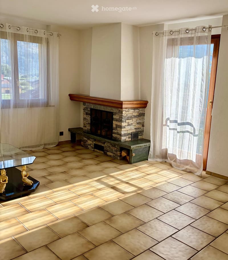 Living room with tiled floor, fireplace, glass table, and decorative statue.