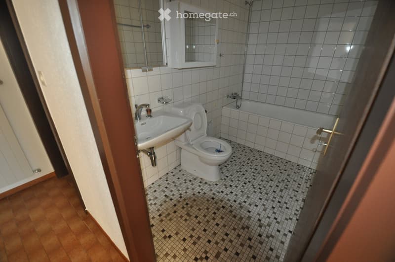 Bathroom with white tiles, a sink, toilet, bathtub, and a mirrored cabinet above the sink.