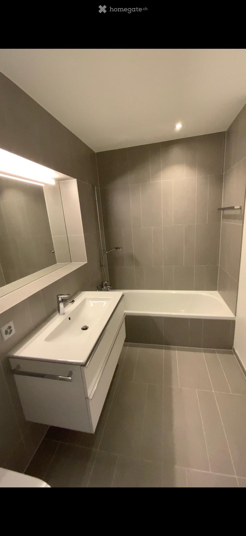 Modern bathroom with a white sink, bathtub, and mirrored cabinet. Features sleek fixtures and neutral tones.
