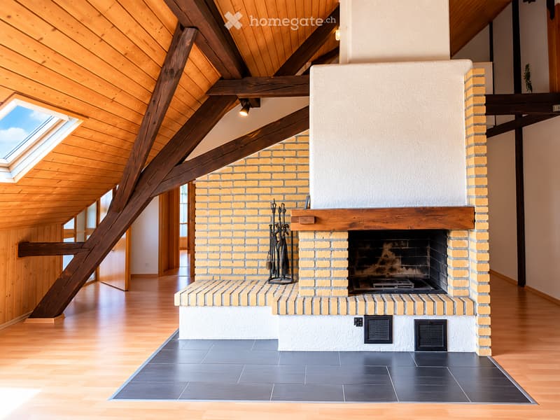 Modern living room with exposed wooden beams, skylight, and a brick fireplace with tools nearby.