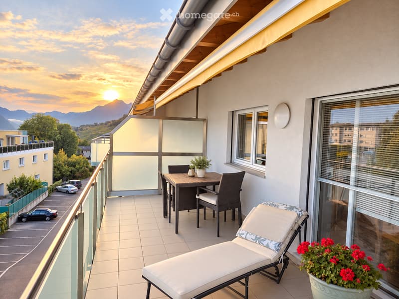 Balcony with a view of mountains and sunset, featuring a lounge chair, dining table with chairs, and potted plants.