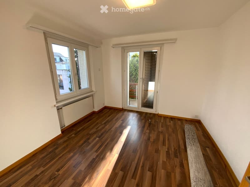 wooden floors, white walls, two windows, sliding glass door to balcony, ceiling light