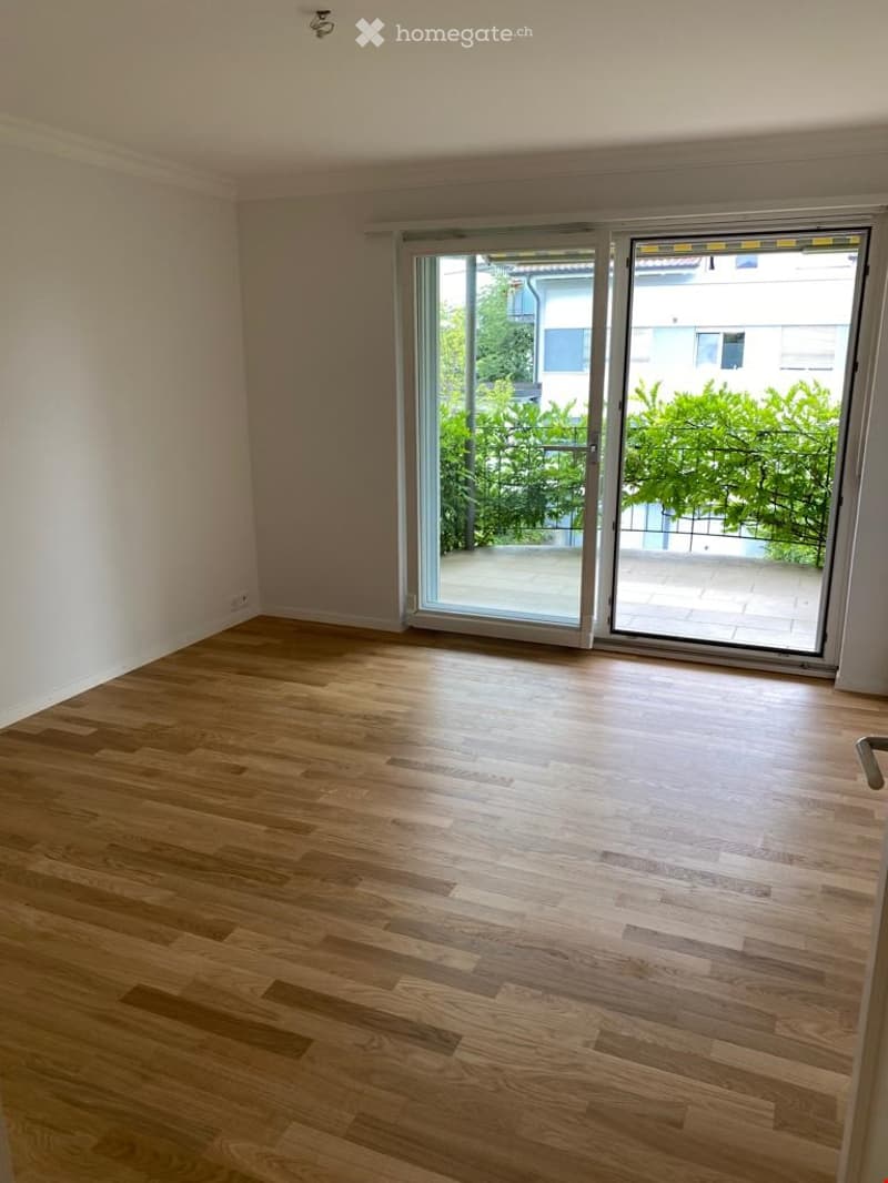 Empty room with wooden flooring and large sliding glass doors leading to a balcony area.
