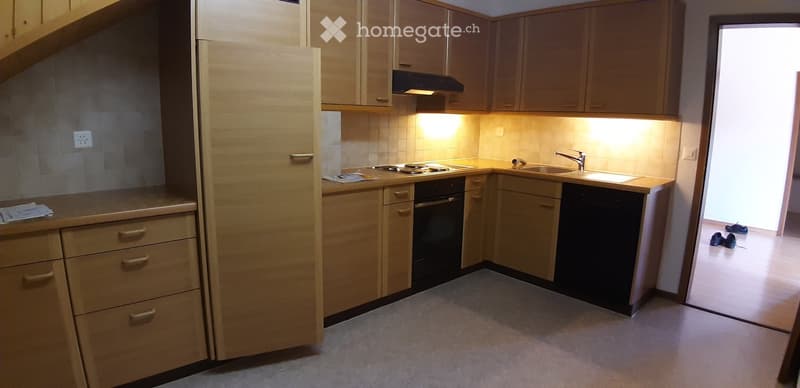 Modern kitchen with light wooden cabinets, stainless steel appliances, and a clean, organized layout.
