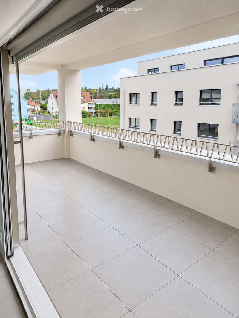 Balcony with tiled floor, metal railing, and a view of a residential area with buildings and greenery.