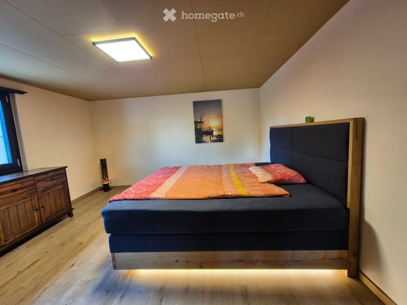 Cozy bedroom with a wooden bed, colorful bedding, a nightstand, and a picture frame on the wall.