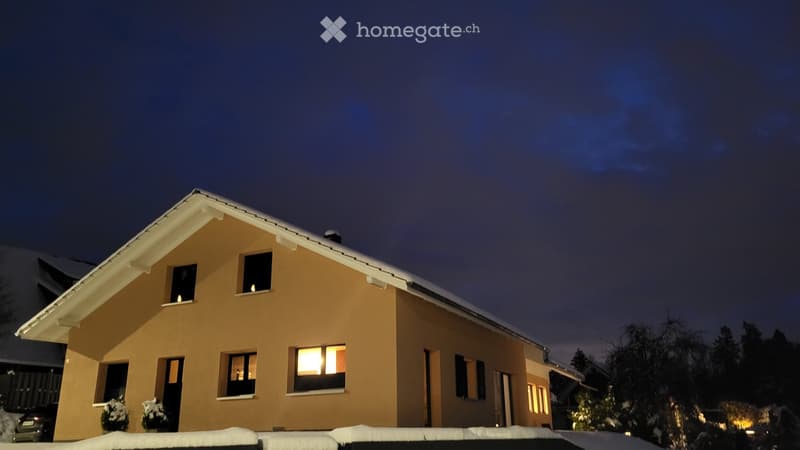 2 story house, beige walls, glass windows, slanted roof, snow, plants