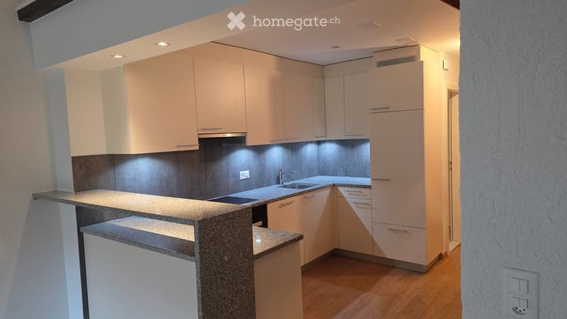 Modern kitchen with light-colored cabinets, granite countertop, and stainless steel sink.