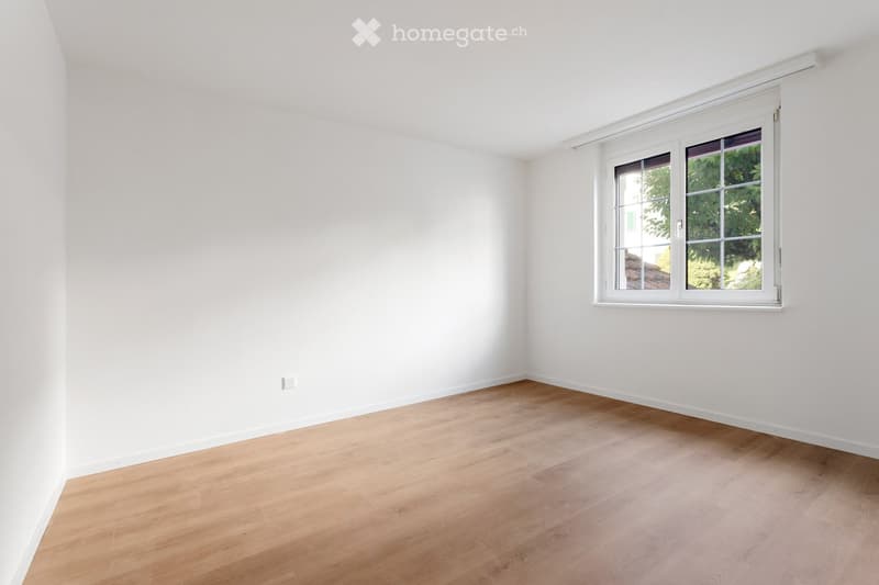 Empty room with white walls, wooden flooring, and a single window with white frame. No furniture or equipment present.