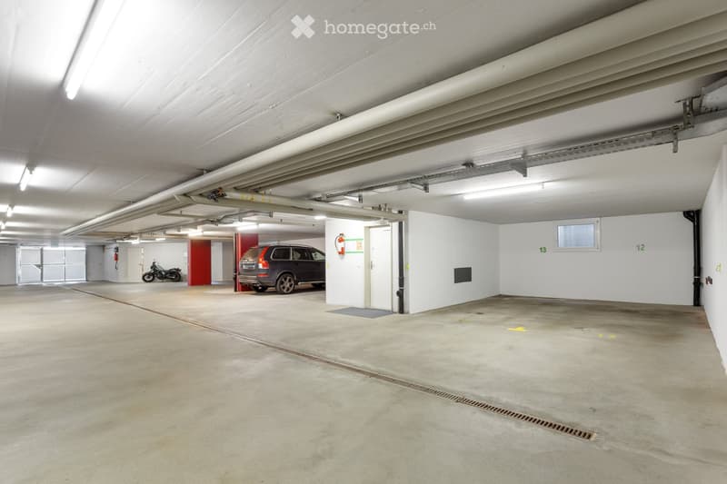 {"type": "Garage", "objects": ["car", "motorcycle"], "description": "Underground parking area with concrete floors, white walls, and fluorescent lighting. Features a parked car, a motorcycle, and numbered parking spaces.", "localized_descriptions": {"EN":