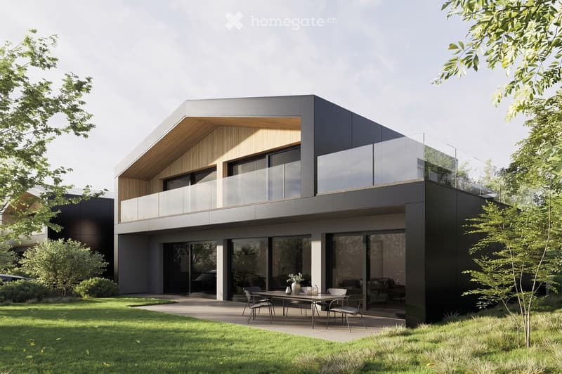Modern two-story house with dark grey and light wood exterior, large glass windows, and a balcony on the upper level. The ground floor features an outdoor seating area with a table and chairs.