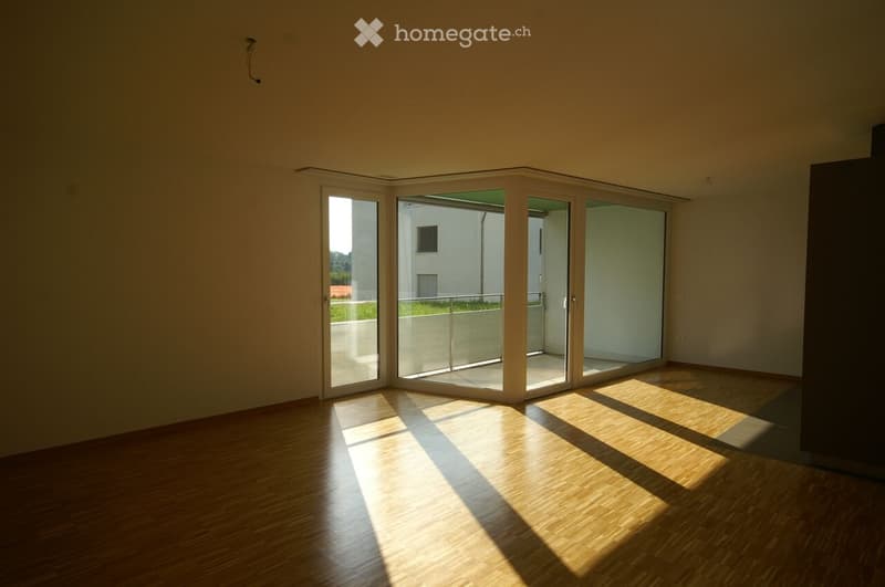 Empty room with wooden flooring and large sliding glass doors leading to a balcony area.
