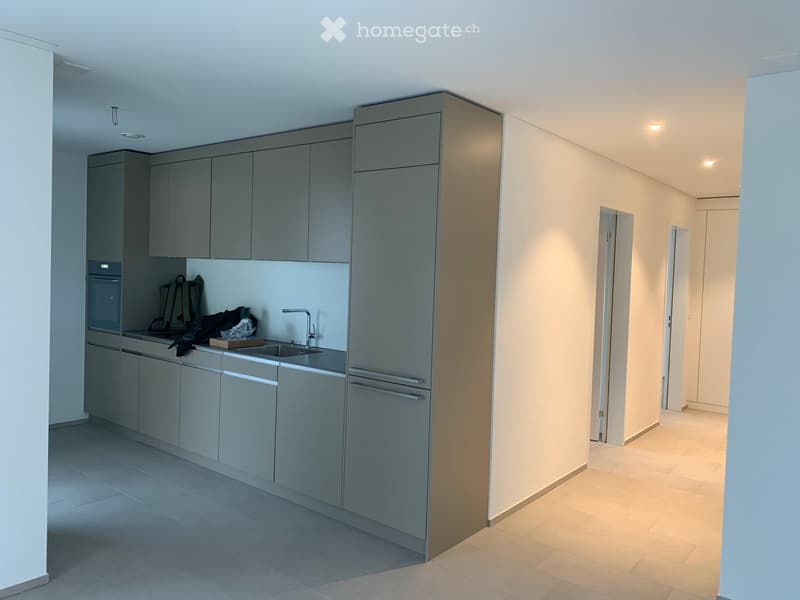 Modern kitchen with grey cabinets, a sink, and an oven. The space is clean and well-lit with a neutral color palette.
