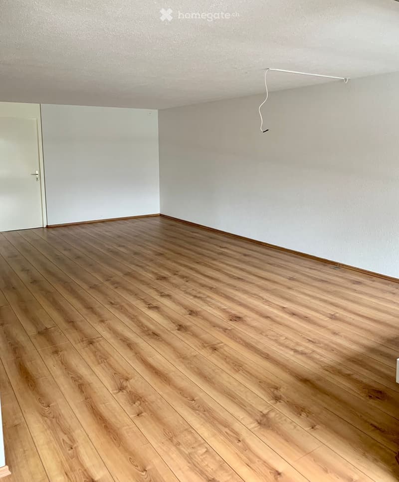 empty room with wooden floors, white walls, and a white door
