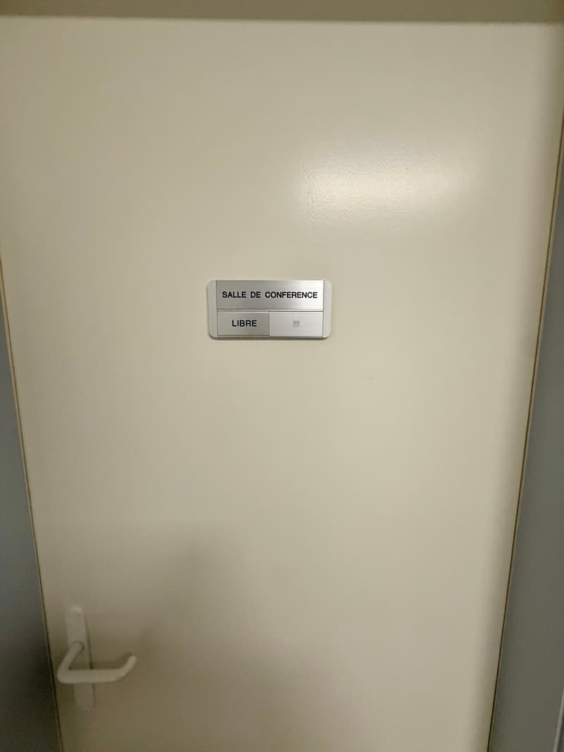 A closed white door with a silver label reading 'SALLE DE CONFERENCE LIBRE'.