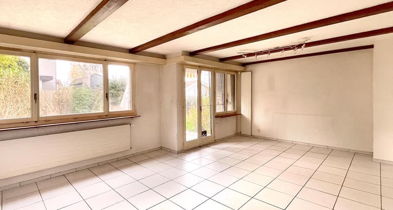 Empty room with white tiled floor, large windows, wooden beams on ceiling