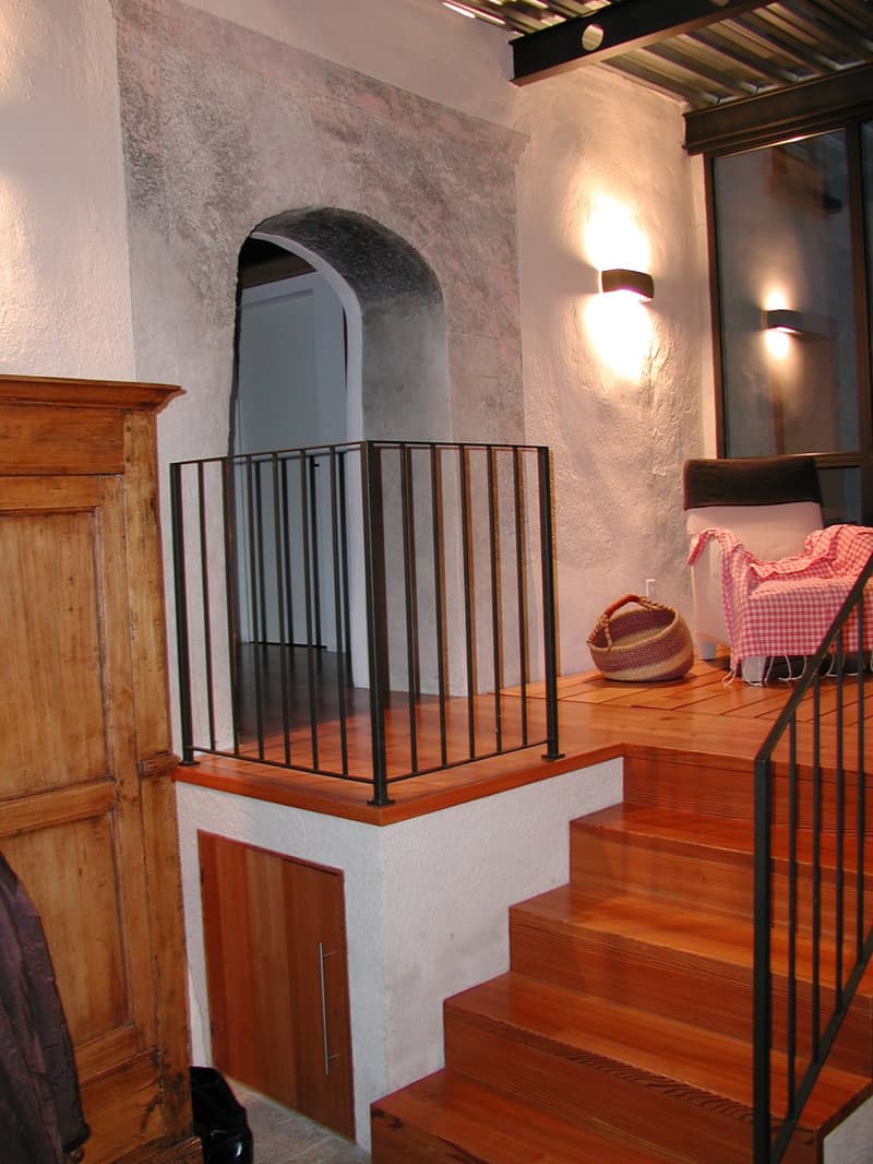 wooden stairs, wooden floor, black railing, wooden door, wall lamp