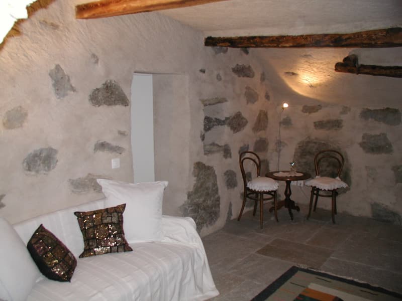 Stone walls, white sofa, two chairs, small table, rug, lamp