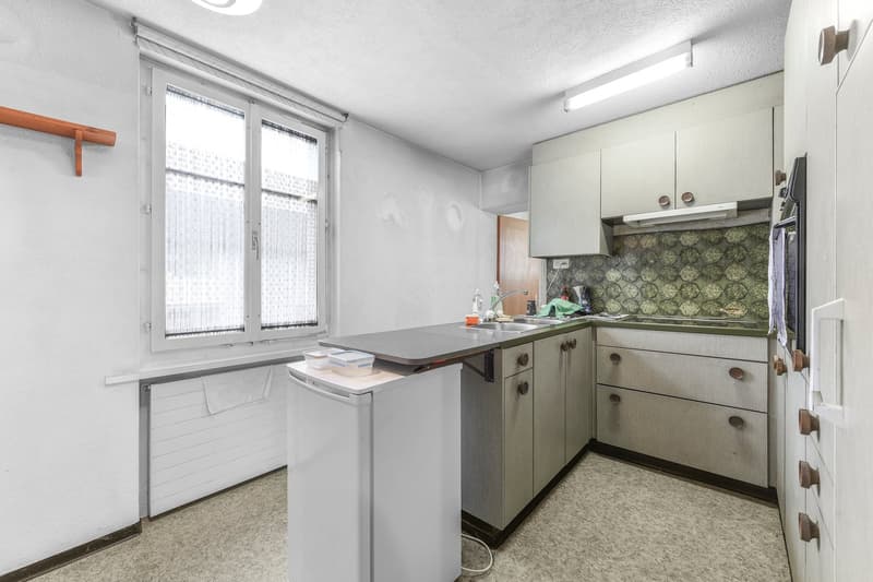Small kitchen, under-counter refrigerator, large sink, white tiled backsplash, white ceiling light