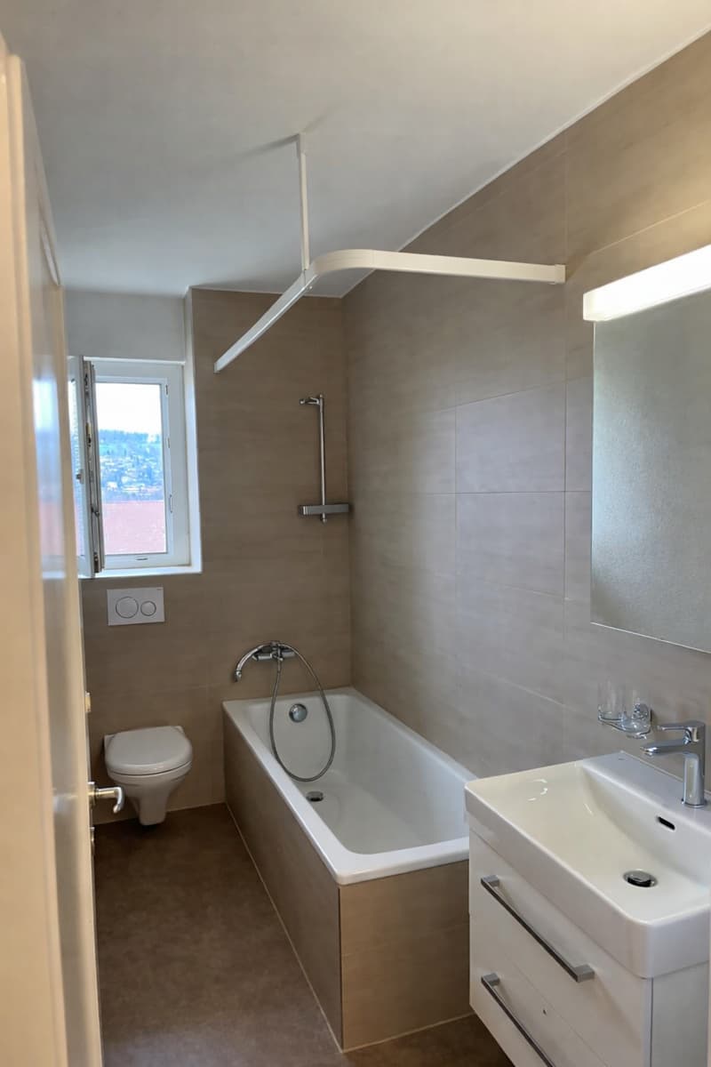 Bathroom with bathtub, toilet, sink, mirror, and window