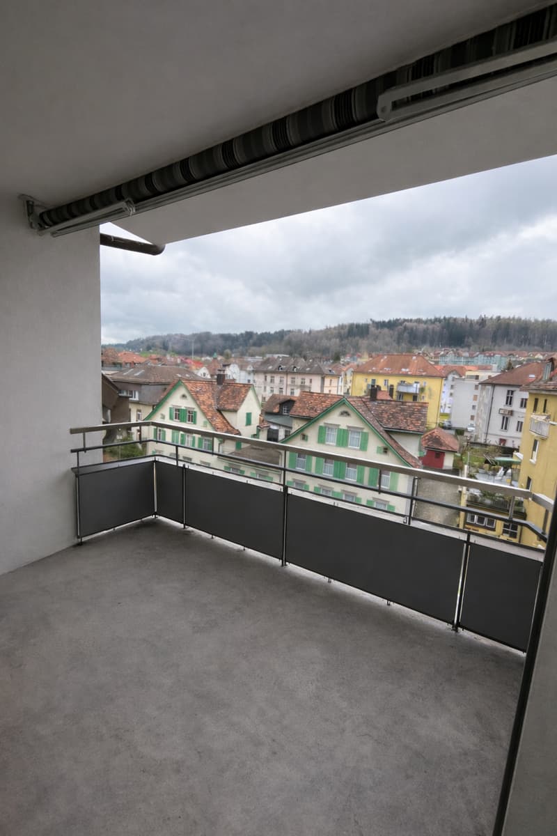 empty balcony with metal railings, concrete floor, view of the city