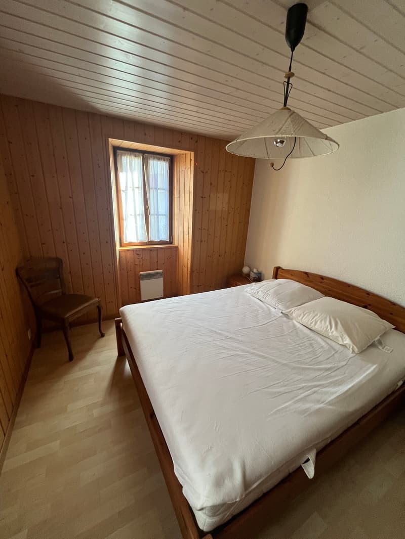 bedroom with wooden walls, bed, chair, window, lamp