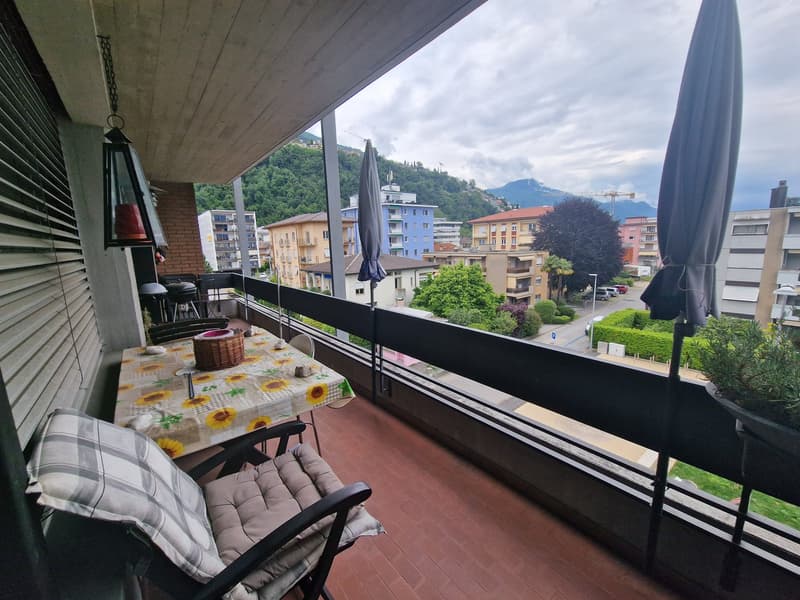 Balcony with table, chairs, umbrellas, and a view of the city