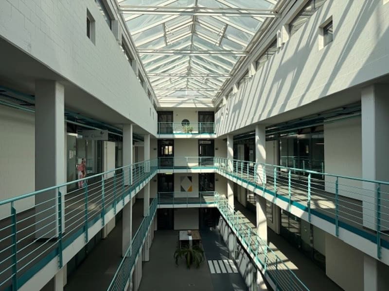Multi-story building with glass roof, multiple floors, balconies, and a central atrium.