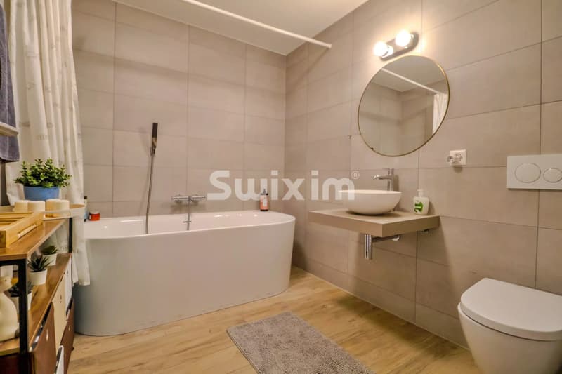Salle de bain moderne avec baignoire et lavabo suspendu.