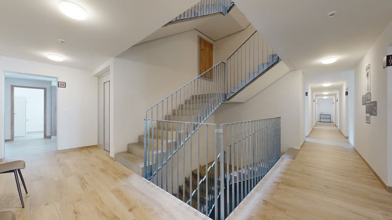 Wooden flooring, white walls, modern staircase, metal handrail, metal ceiling fixtures, no visible windows, number 111