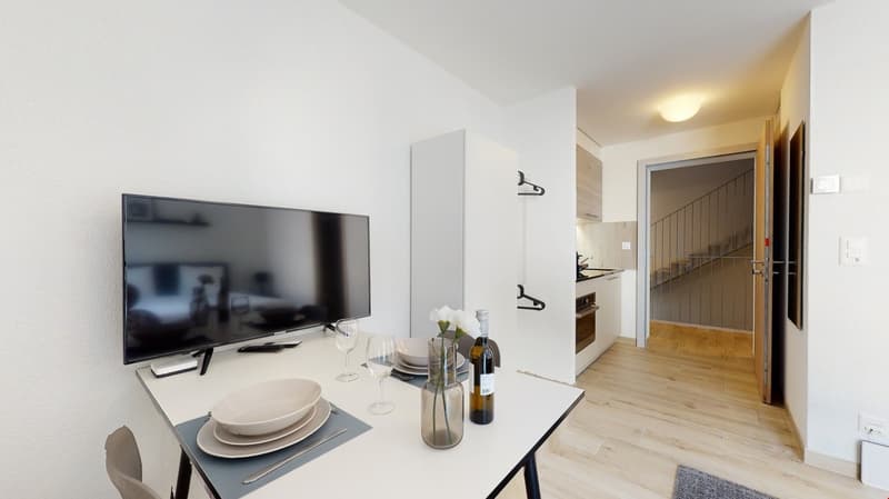 modern, clean, white table, flat screen TV, vase with flower, wine glasses, knife and plates