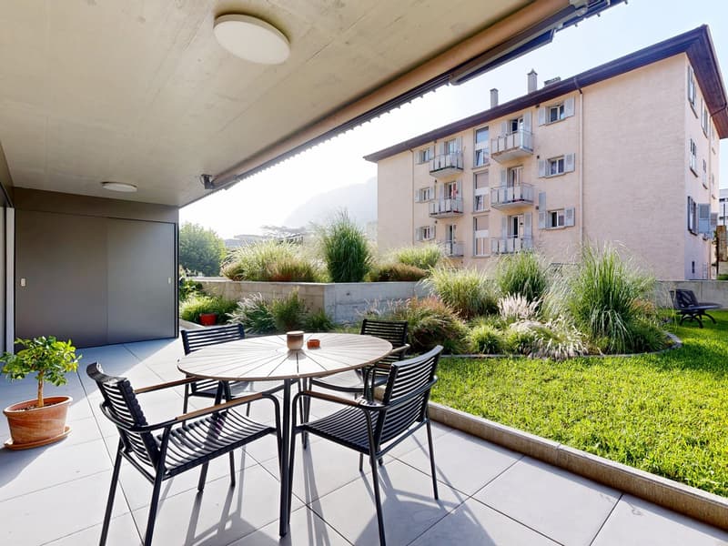 Tiled floor, table and chairs, potted plant, concrete barrier, grass, wall, outdoor door, balcony light
