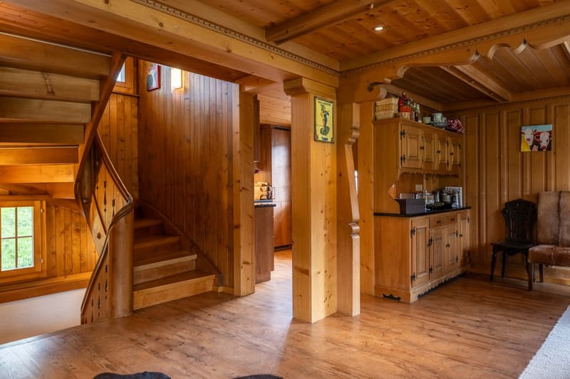 Wooden walls, wooden flooring, wooden staircase, wooden kitchen cabinets, wooden seating with cushions, framed pictures on the wall